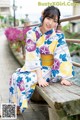 A woman in a kimono sitting on a wooden bench.