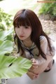 A woman in a sailor outfit crouching down next to a plant.