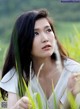 A woman in a white dress sitting in a field of tall grass.