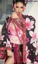 A woman in a pink and black kimono posing for a picture.