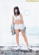 A woman in white shorts and a white bra top posing for a magazine.