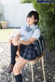 A woman in a school uniform sitting on a chair.