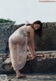 A woman in a white dress sitting on a stone wall.