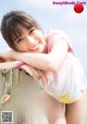 A young woman leaning on a wooden post on the beach.