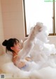 A woman is taking a bath in a bathtub filled with foam.