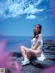 A woman sitting on a rock by the ocean.